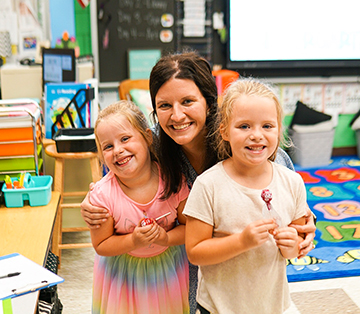 Teacher posing for a pic with two happy little girls